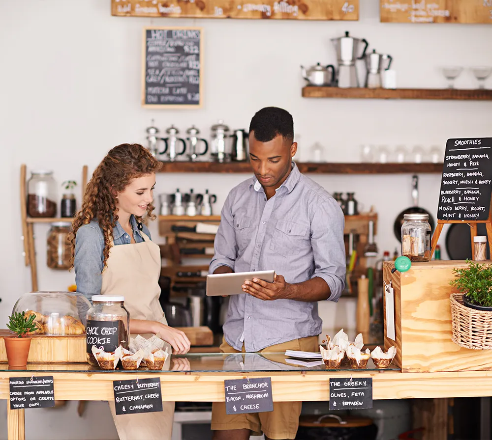 Two baristas using a tablet, inside a cafe.